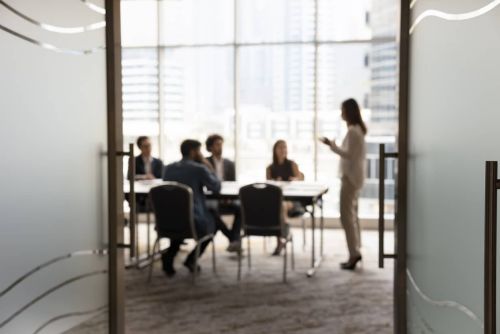 Silhouettes of businesspeople gathered in conference room, blurred view