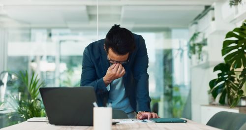 Businessman, stress and headache in office for finance, banking fraud and accounting mistake at laptop. Accountant, tech and frustrated in financial agency for admin crisis, economy fail and anxiety