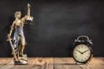 Statue of Lady Justice with Alarm Clock on Black Board Background