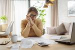 Mature woman contemplating bills and tax papers at home